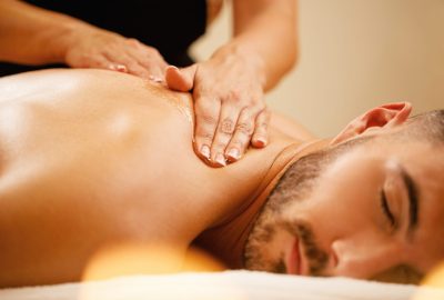 Close-up of man enjoying in relaxing back massage with honey at the spa.